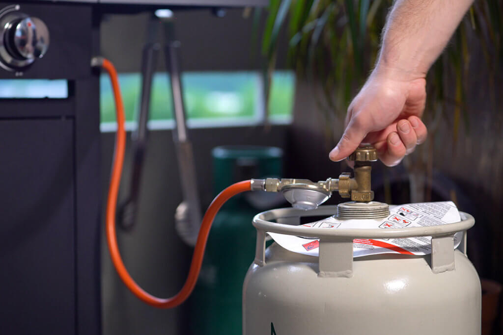 Mann dreht Gas fuer Gasgrill auf