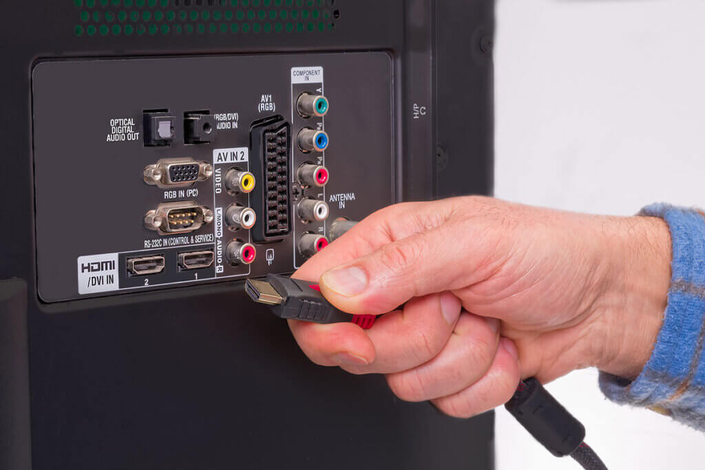 Mann schlieĂt HDMI Kabel an Fernseher an