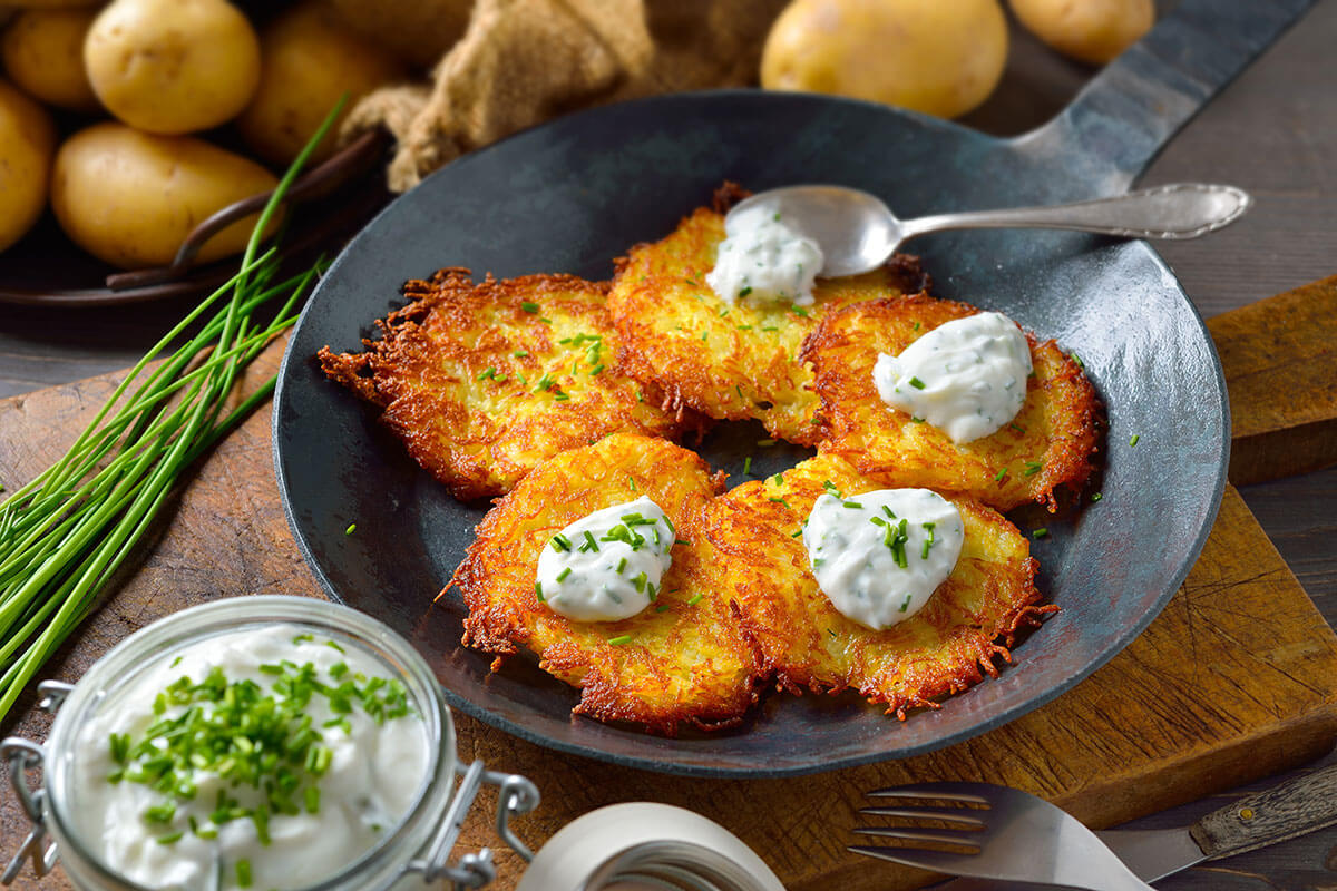 Mehrere Roesti mit Kraeuterquark lecker in Eisenpfanne angerichtet