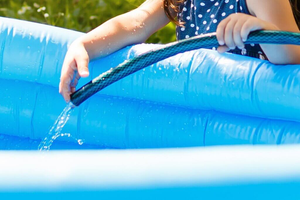 MĂ€dchen fĂŒllt Pool mit Wasser
