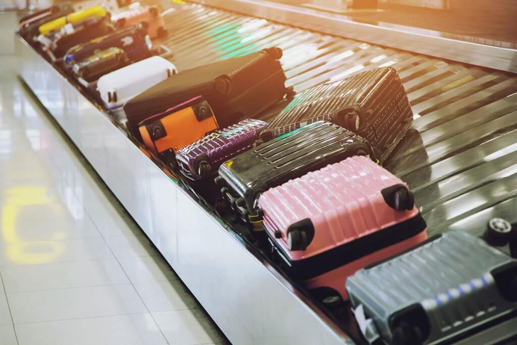 Mehrere Hartschaltenkoffer liegen auf Paketband am Flughafen