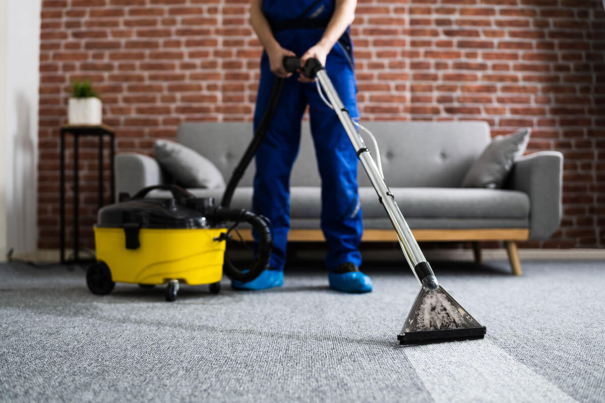 Mann reinigt Teppich mit Industriesauger