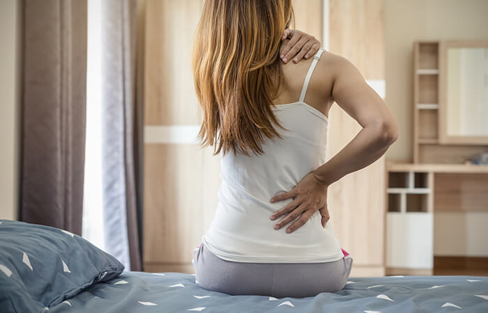 Frau mit RĂŒckenschmerzen auf Bett
