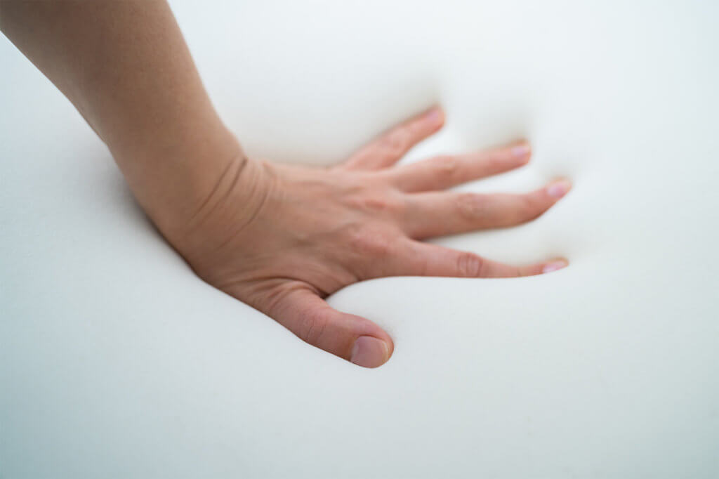 Hand ueberprueft die Weichheit einer Matratze