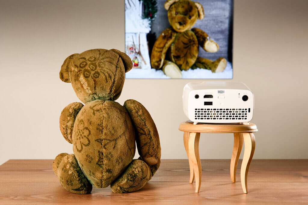 TeddybÀr vor Leinwand neben Beamer