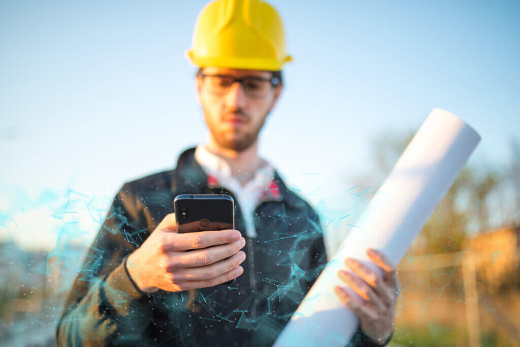 bauarbeiter mit schutzhelm hÀlt ein outdoor-smartphone in der hand