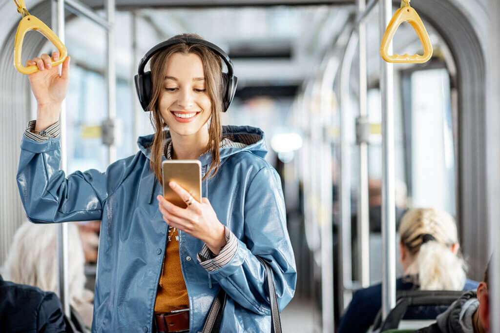 Junge Frau in Bahn mit Kopfhörern auf Kopf