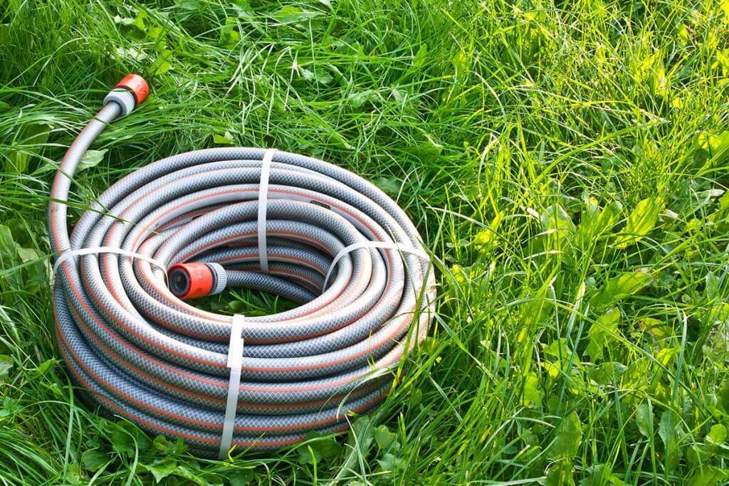 neuer Gartenschlauch liegt auf Wiese