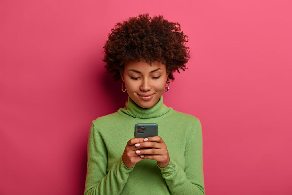 Frau mit Smartphone vor pinker Wand
