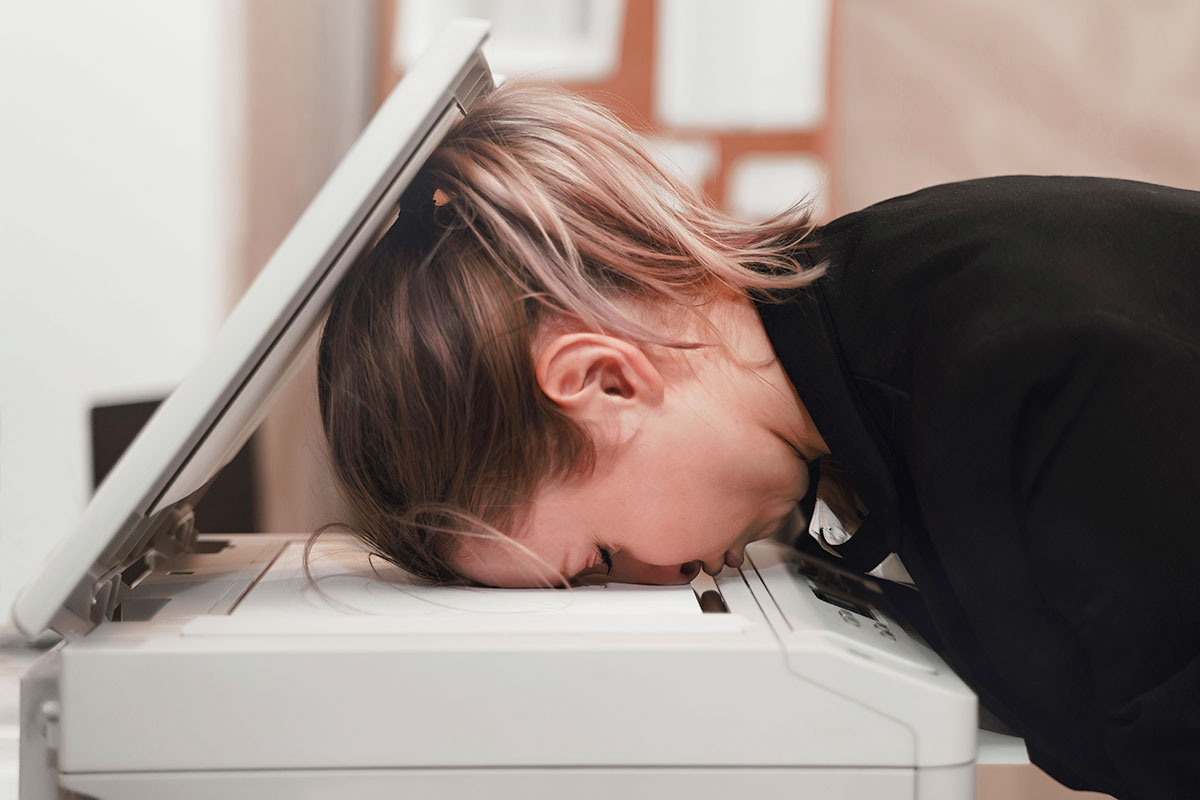 Frau drĂŒckt ihren Kopf auf Drucker