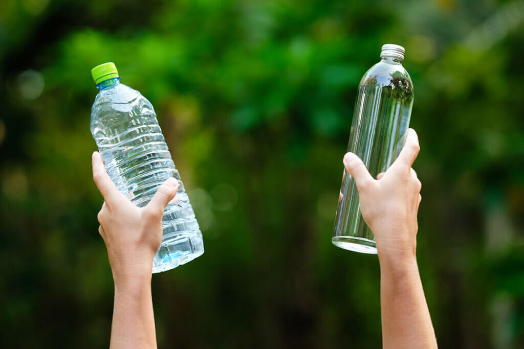 HĂ€nde halten Plastik- und Glasflasche hoch